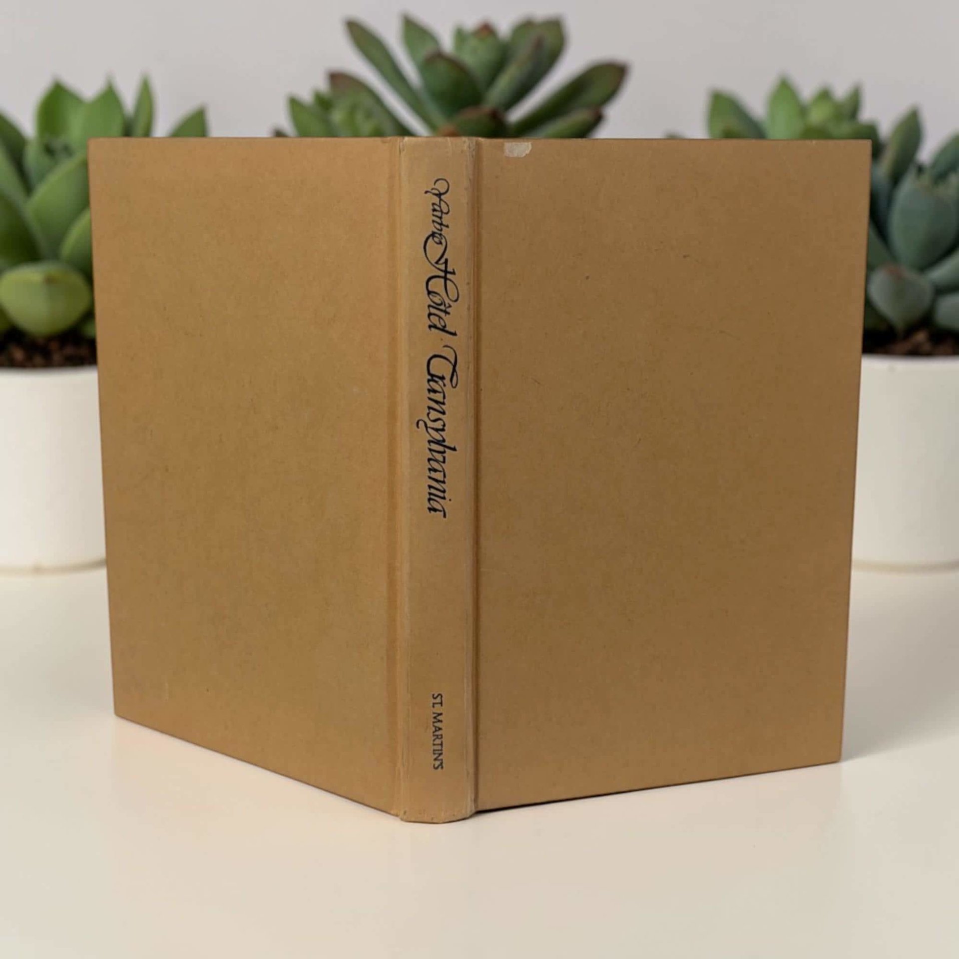 A vintage hardcover book with a tan cloth binding and dark blue text on the spine. The title page displays "Hotel Transylvania a novel of forbidden love" in a stylized serif font above the author's name.