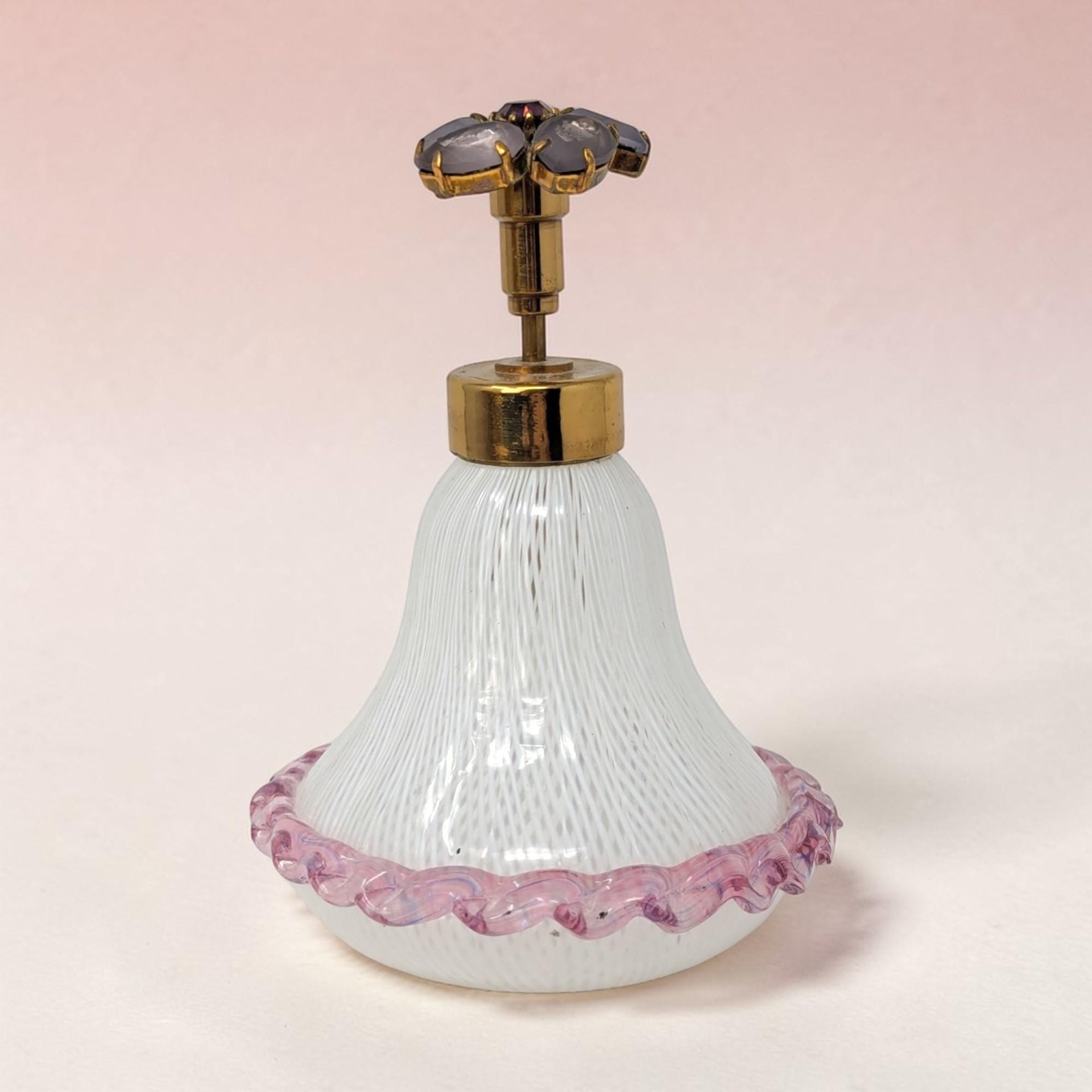 A bulbous glass perfume bottle with a swirl of white, pink, and yellow filigree ribbons. It features a clear, gold-flecked orb stopper and a flared rim. The delicate internal latticework creates a complex, spiraling cage effect.
