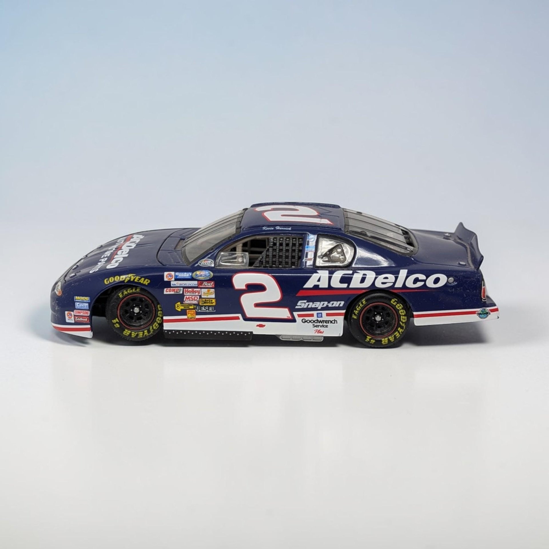 A 1:24 scale die-cast race car with a deep blue body and white and red "ACDelco" branding. The hood features the number "2" and "ACDelco" logo, with various contingency sponsor decals across the front fenders. The car has black wheels and a detailed black interior.