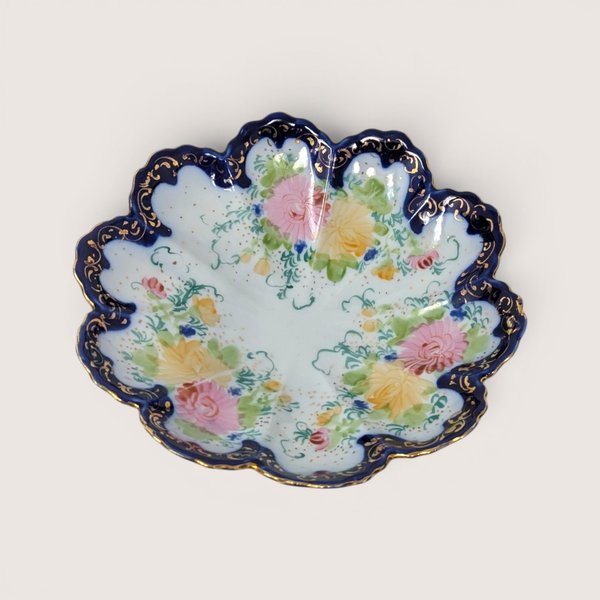 Vintage hand-painted porcelain bowl featuring a scalloped cobalt blue and gold gilt rim with delicate floral details.