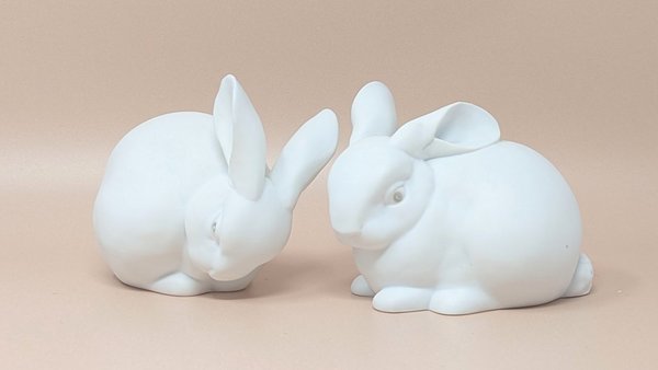 Pair of vintage Dept. 56 white porcelain bunnies in resting poses. Features a soft matte finish with realistic ear and fur detailing.