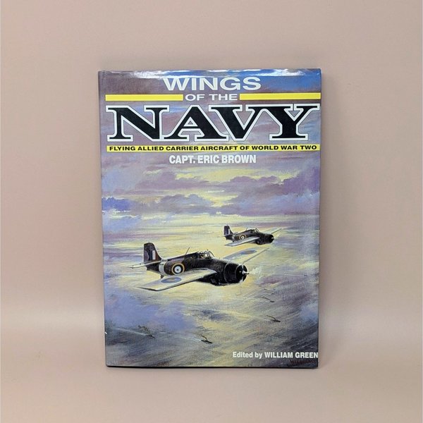 Hardcover book titled "Wings of the Navy" by Capt. Eric Brown. Dust jacket features a painting of two Allied fighter planes flying over a sunset-lit sea. 1987 edition.