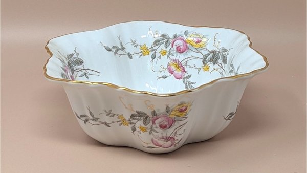 Scalloped white porcelain serving bowl with pink and yellow rose transfers. Features a hand-applied gold rim and a fluted, lobed body. Made in Germany, early 20th century.