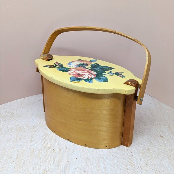 Vintage Basketville wood bucket with a swing handle and fitted lid. Features a hand-painted pink rose and blue floral bouquet on a cream-colored lid. Natural light wood finish. 11.5 inches long.