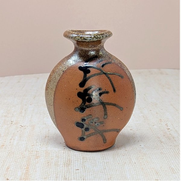 Vintage Brad Lee Henry studio pottery vase. Features a bulbous body in earthy red-brown with a metallic tenmoku drip glaze and black calligraphic slip-painted accents. 5 inches tall.