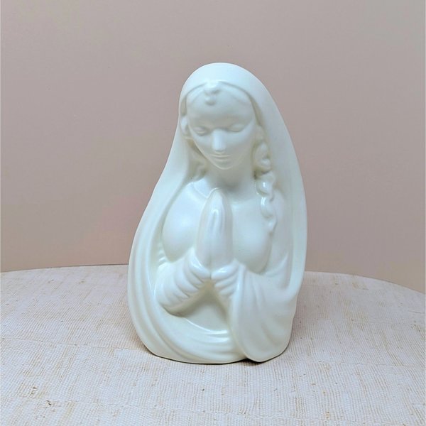 Mid-century white ceramic planter featuring a bust of a praying Madonna. Smooth, semi-matte ivory finish, flowing drapery, and serene facial expression. Hollow back for plants or stems.