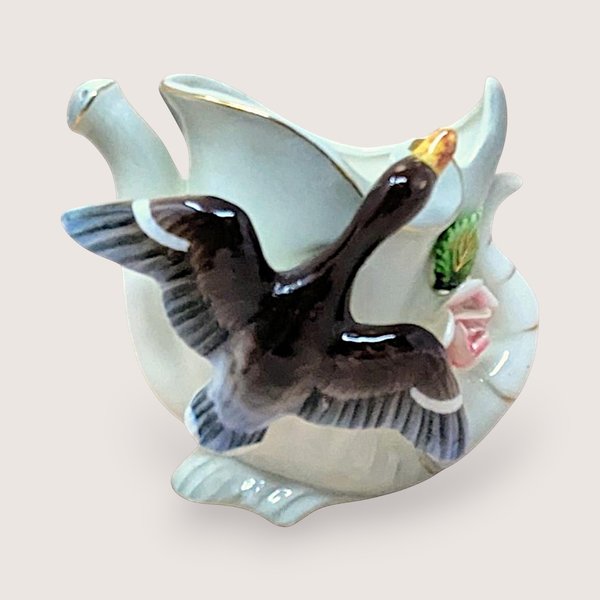 A vintage white ceramic watering can vase from Thames Japan. Features a hand-painted duck in flight across the front with pink floral accents and gold trim along the rim and spout. 4.25 inches tall.