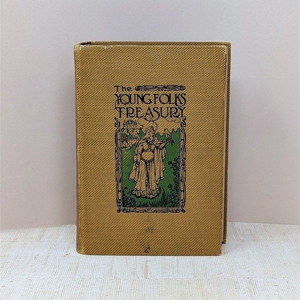 Antique book with a golden-yellow textured cloth cover. Features an Art Nouveau illustration of a woman with a hawk and a castle. Titled "The Young Folks Treasury" in stylized black font. Aged, tactile fabric finish.