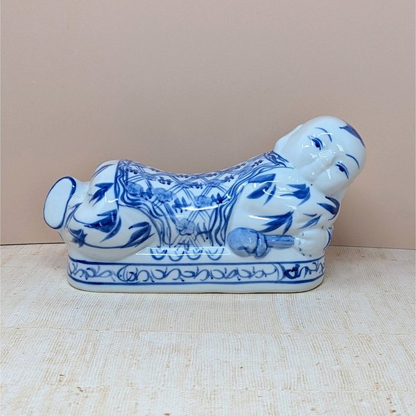 A horizontal porcelain headrest shaped like a reclining child. Featuring a crisp white ground with traditional cobalt blue floral and scroll patterns. Glossy vitrified texture with hand-painted facial details.