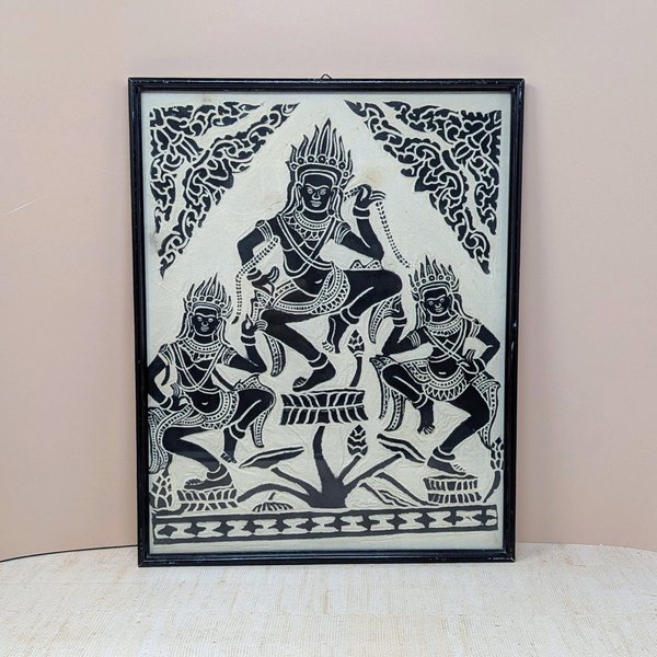 A vertical framed art piece on textured rice paper featuring three Apsara dancers in traditional Cambodian headdresses and poses. Bold black ink on a cream-white background. Framed in a minimalist black wood frame.