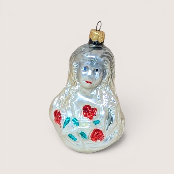 Vintage blown glass Christmas ornament of a girl with long hair, red lips, and red roses, isolated on a light background.