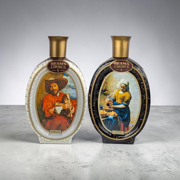 Two oval ceramic decanters. One is white with a painting of a man playing bagpipes; the other is black with Vermeer's Milkmaid painting. Both have gold flared tops.