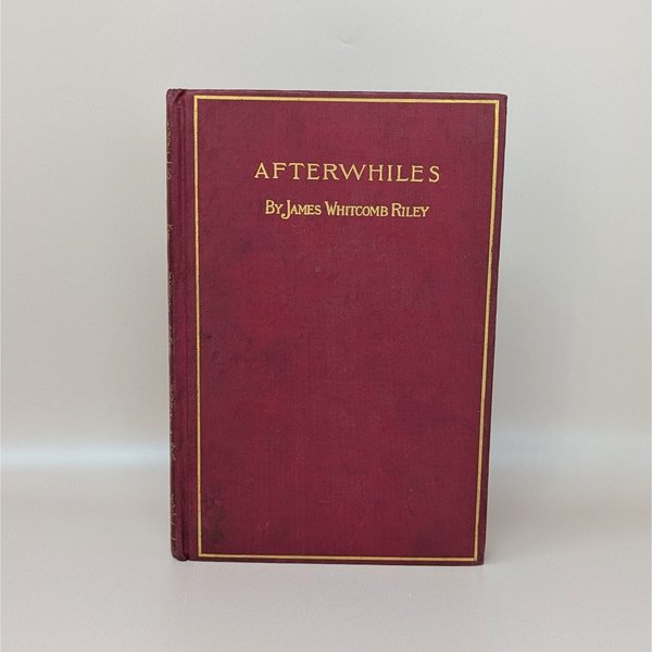 A burgundy cloth-bound hardcover book with a gilded rectangular border and gold typography for Afterwhiles by James Whitcomb Riley against a neutral background.