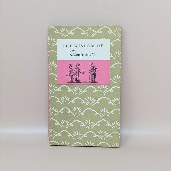 A slim hardcover book with a sage green and cream floral pattern, featuring a central pink and white label with the title The Wisdom of Confucius and a small illustration of three figures against a neutral background.