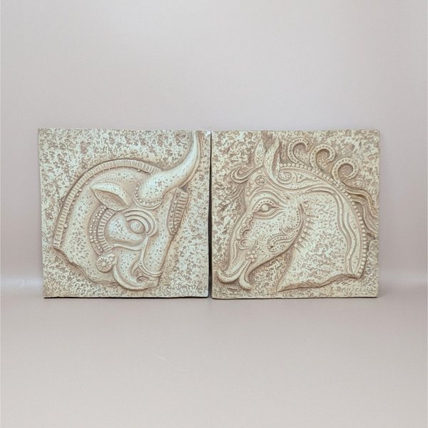 A pair of square vintage plaster wall plaques by Z. Danjell featuring stylized relief carvings of a horse and a bull in a Greek Brutalist style.