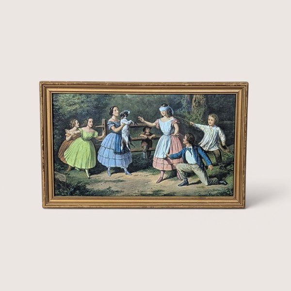 A vintage framed Currier and Ives print titled Blind Man's Buff on a tan textured background. The mid-century horizontal lithograph depicts Victorian-era children playing a blindfolded game in a lush green backyard space.