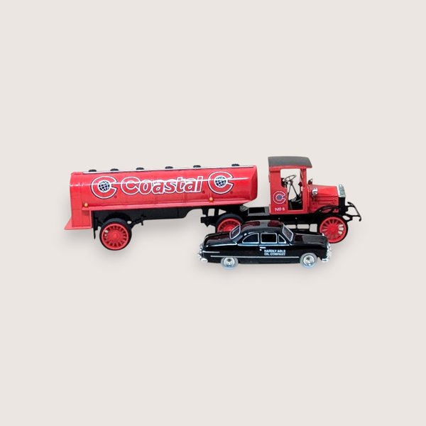 A vintage miniature red Coastal oil tanker truck alongside a small black car on a plain light background.