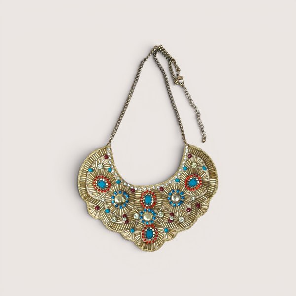 Intricate gold beaded bib necklace featuring turquoise, red, and blue accents with clear rhinestones.