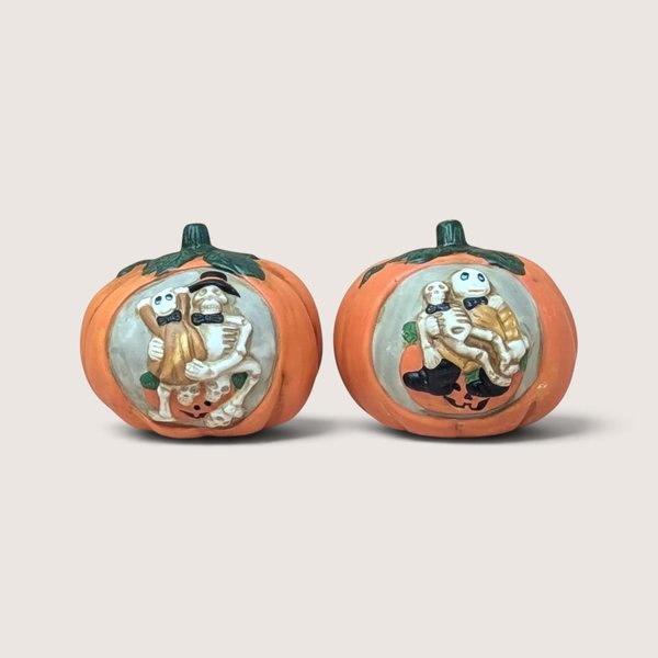 Two vintage ceramic pumpkin tealight candle holders featuring hand-painted relief panels of skeleton couples.