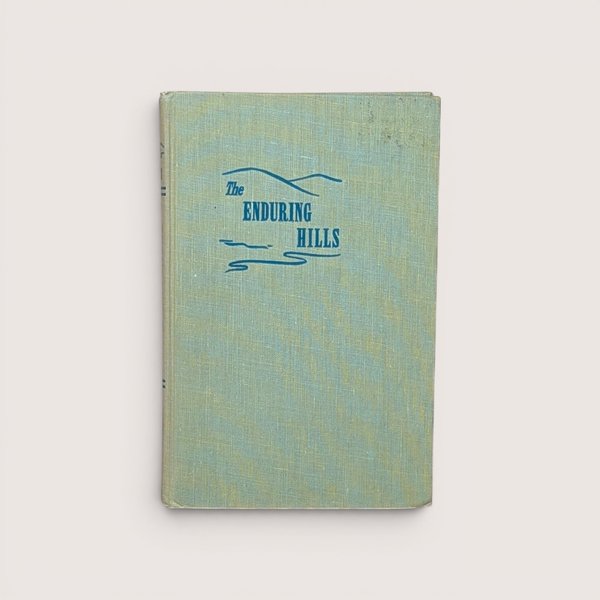 A vintage light green cloth hardcover book titled The Enduring Hills with a simple blue hill illustration on the cover.