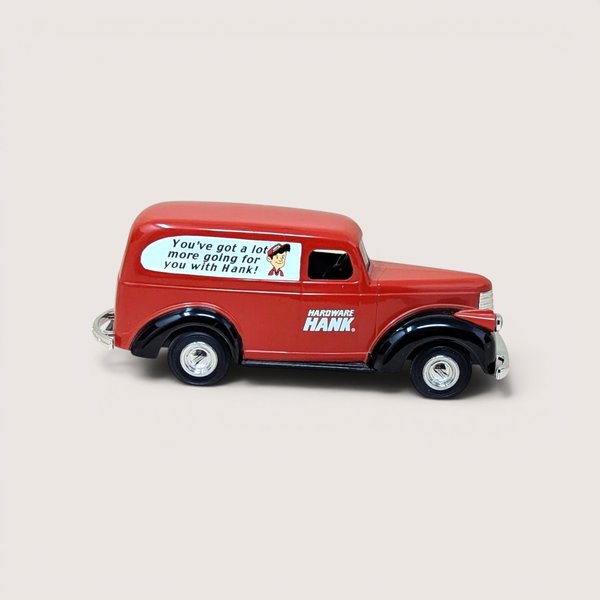 A red and black die-cast 1946 Chevy Suburban coin bank van featuring Hardware Hank advertising on a plain background.