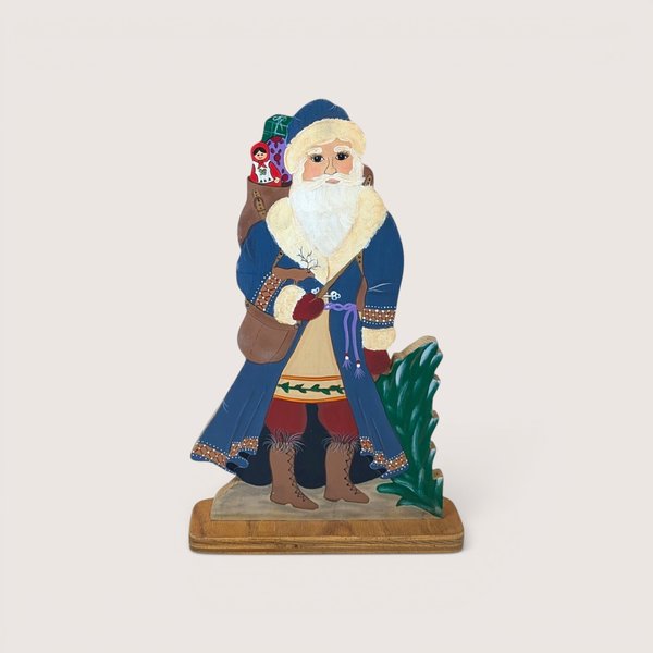 Hand painted wooden Santa Claus figure wearing a blue coat and holding a sack with a matryoshka doll.