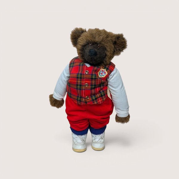 A jointed handmade artist teddy bear named Ted Edward wearing a plaid vest red trousers and white sneakers