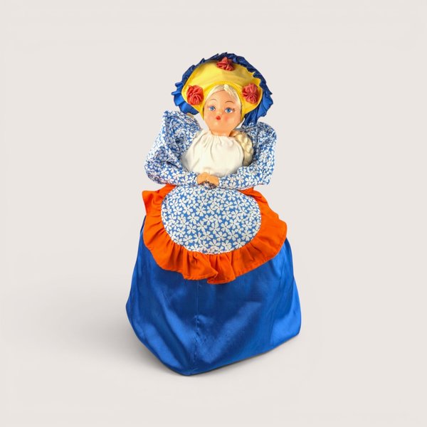 A vintage handmade tea cozy doll featuring a plastic face blonde braid and a large blue and orange fabric skirt