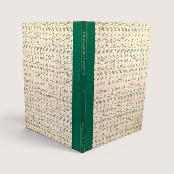 A vintage hardcover book standing upright showing a green cloth spine and patterned cream and green boards