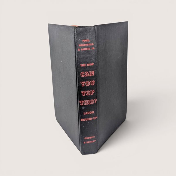 Vintage hardcover book spine in textured black cloth with bright red embossed text reading The New Can You Top This.