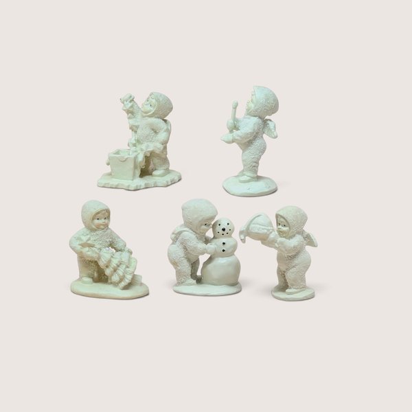 A set of five miniature Department 56 Snowbabies figurines and their matching patterned boxes against a neutral background.