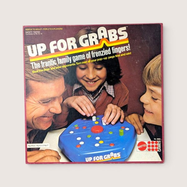 Vintage Up For Grabs board game box cover featuring a photograph of a smiling family playing a mechanical blue game.