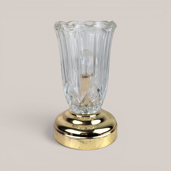 Clear glass tulip chimney lamp with a brass base on a plain background.