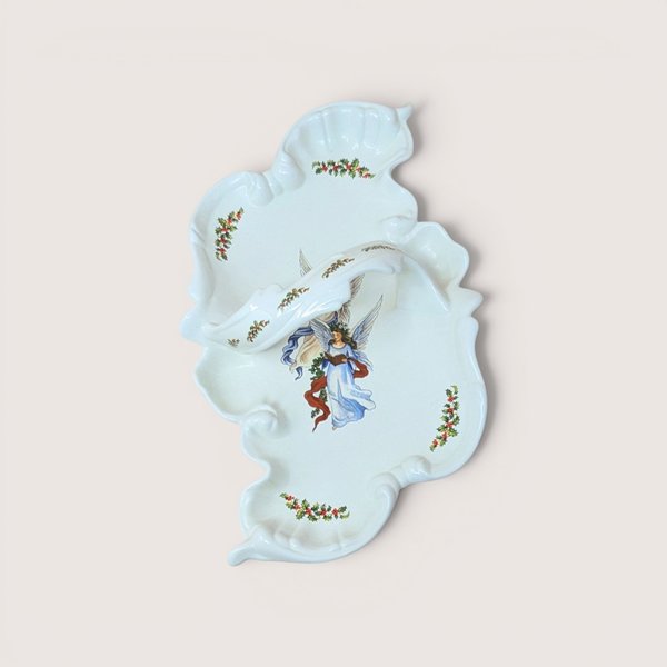 White ceramic divided serving dish with an integrated center handle, featuring an illustration of an angel holding a book surrounded by holly leaf accents, centered on a plain linen background.