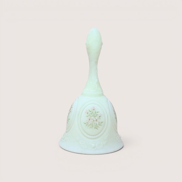Light green custard glass dinner bell featuring a hand-painted bunch of small white and pink flowers within an oval medallion, centered on a plain linen background.