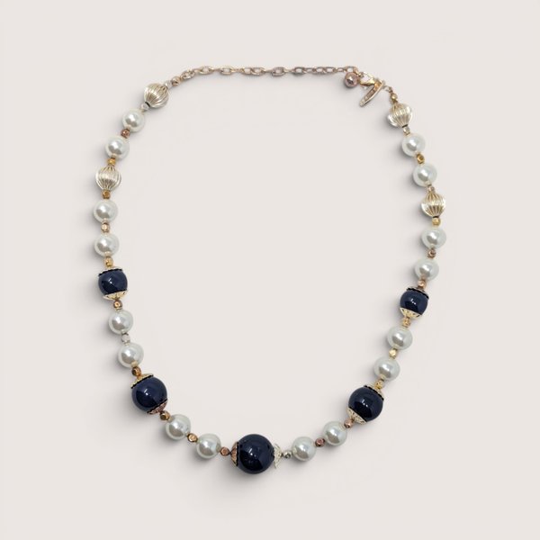 Vintage George statement necklace with dark blue glass beads, white pearls, and gold accents on a linen background