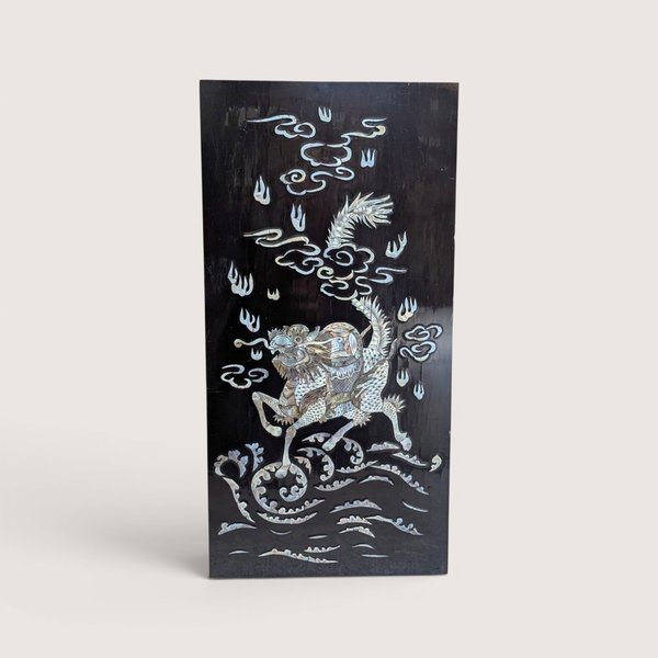Vintage Asian black lacquer wood wall panel with iridescent mother of pearl inlay depicting a qilin on a linen background