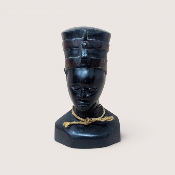 Vintage hand-carved dark wooden bust depicting Queen Nefertiti wearing a traditional high crown, accented with a small piece of natural twine tied in a knot around the neck, centered on a plain linen background.