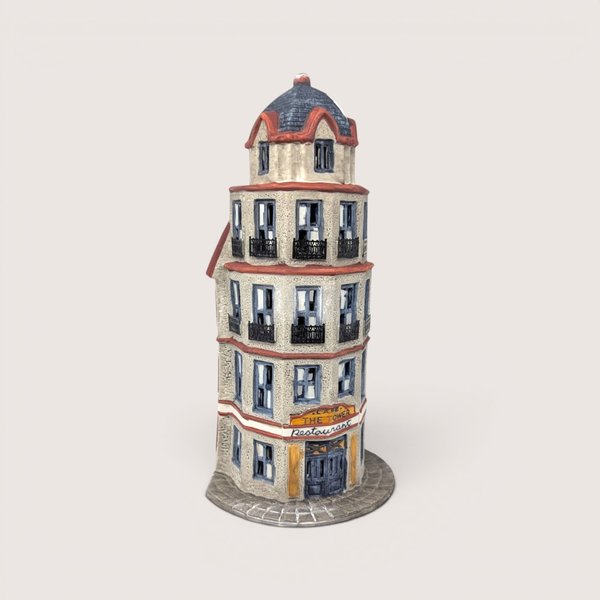 A handpainted porcelain Dept 56 The Tower Cafe flatiron style building on a linen background