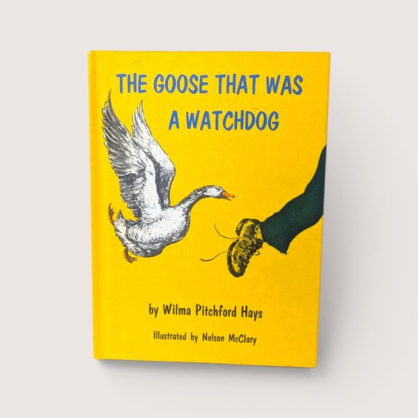 An illustrated bright yellow book cover showing a goose flying toward a person's foot on a plain background