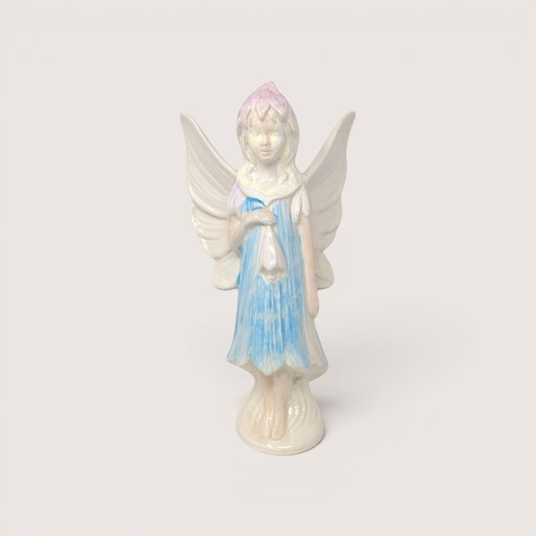 A vintage hand-painted ceramic fairy figurine with large white wings, a blue dress, and iridescent pastel hair.