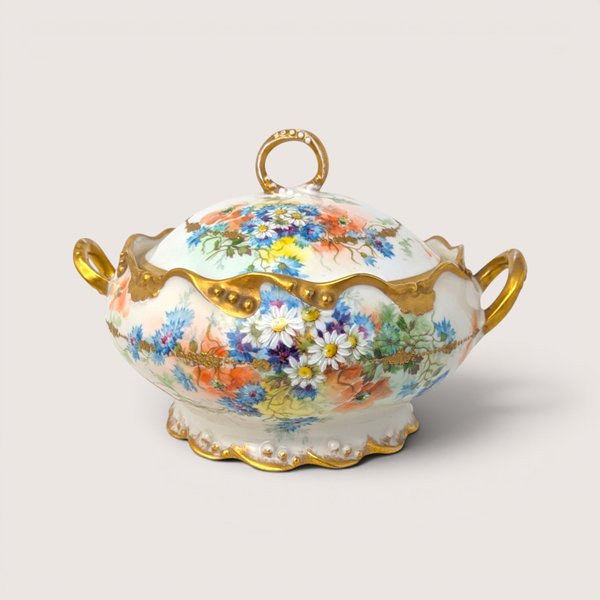 An antique white porcelain covered tureen painted with vibrant wildflowers and heavy gold trim on a beige background