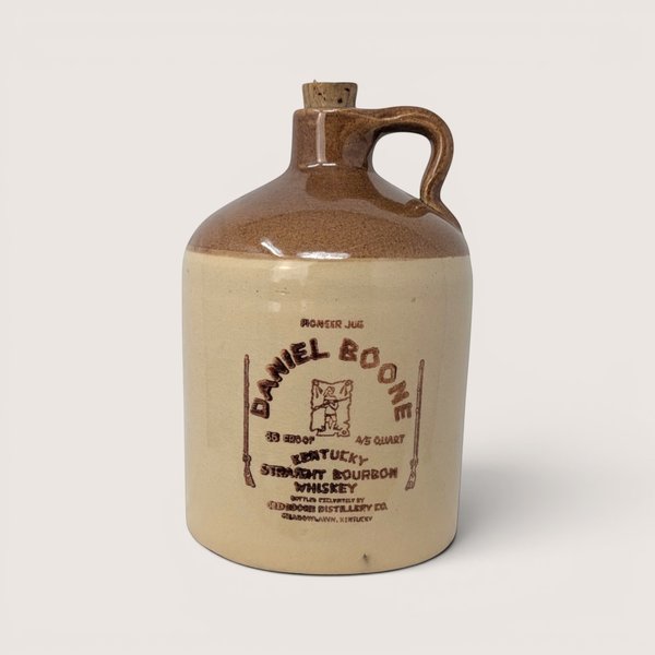 A vintage two tone stoneware Daniel Boone bourbon whiskey jug with a cork stopper on a light cream background