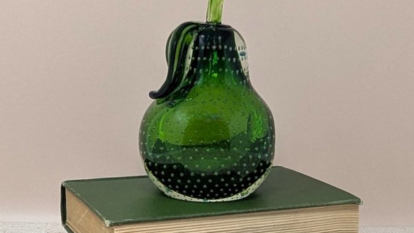 A heavy emerald green glass pear with a clear stem and leaf. The interior is filled with a uniform pattern of tiny air bubbles. It has a flat base and a secondary flat side for angled display.