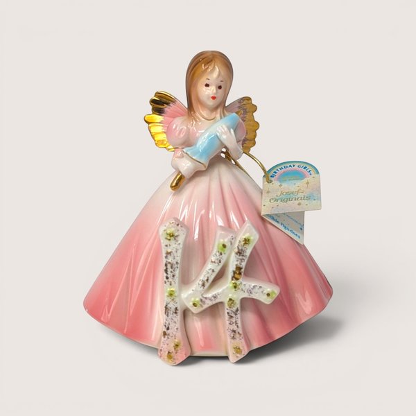 Porcelain birthday angel figurine in a pink gown holding a blue umbrella behind a floral number 14 on a solid background.