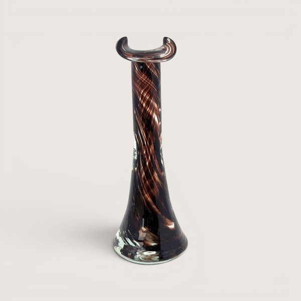 A slender dark brown and amber swirled glass bud vase with a flared base and a crescent shaped rim on a plain background