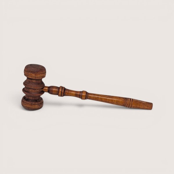 Vintage turned wooden legal gavel with a ridged head resting horizontally.