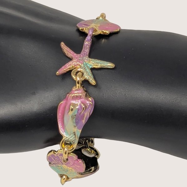 Vintage gold tone enamel link bracelet featuring iridescent pink and teal starfish and seashell charms.