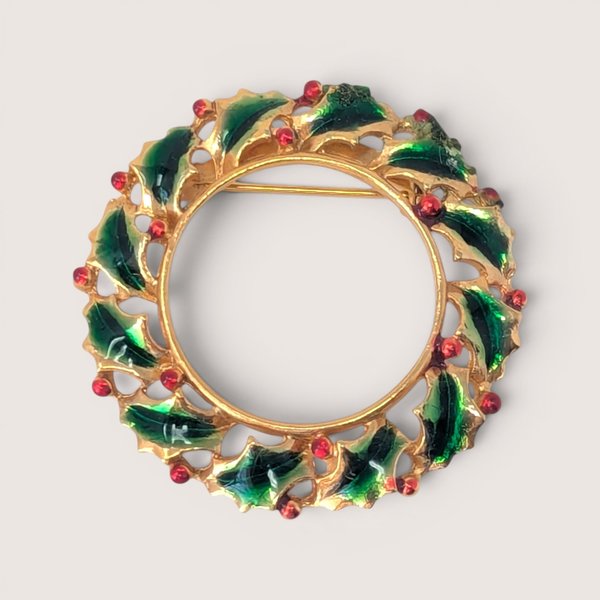 Vintage gold-tone enamel holly wreath brooch with green leaves and red berry details.