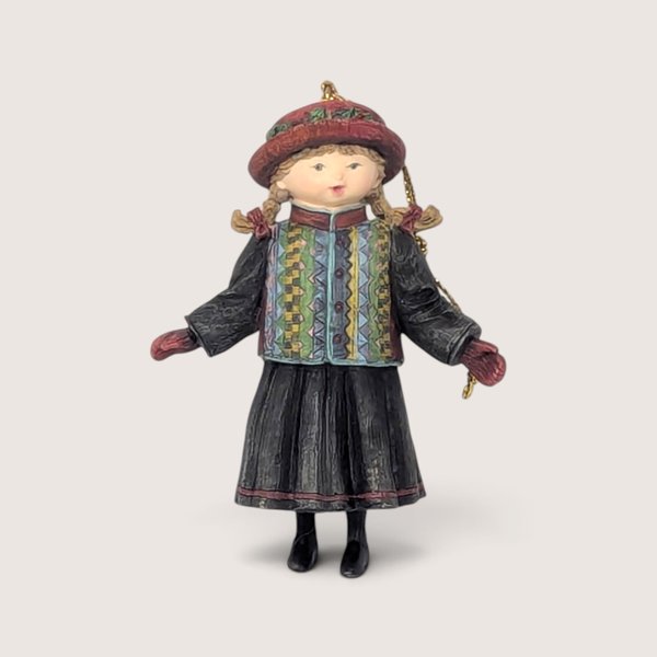 Vintage 1998 Lang and Wise girl resin Christmas tree ornament wearing a patterned jacket and red hat.